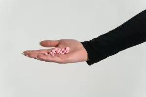 A woman's hand with some pink pills for mental health